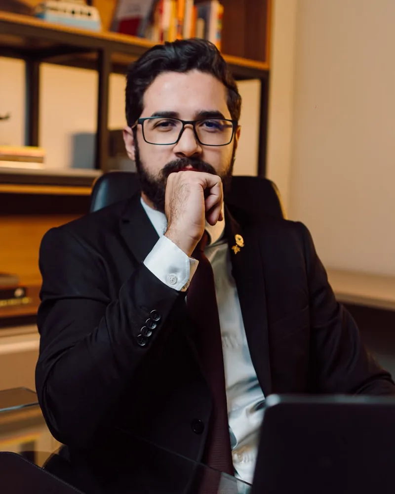 Samuel Brandão, sentado em seu escritório, com a mão no queixo